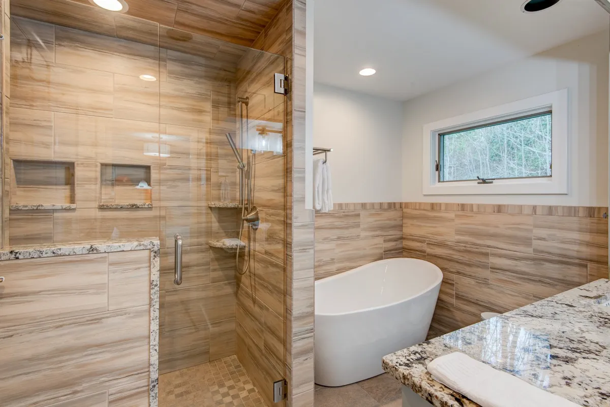 A modern, spa-inspired bathroom with a glass shower, a freestanding bathtub, and a granite countertop. The space feels luxurious and tranquil, emphasizing relaxation and self-care routines.