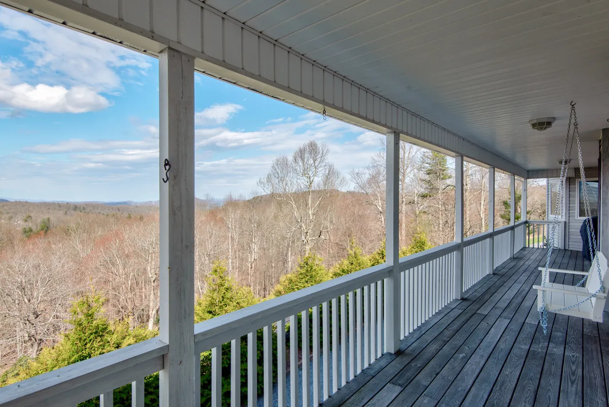 A peaceful exterior scene showing a porch swing and wooden railing overlooking distant mountains and trees. The setting is tranquil, inviting relaxation and connection with nature after a day of adventure.