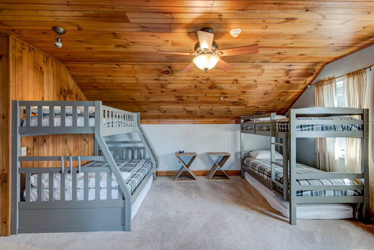 A dedicated bunk area with sturdy wooden bunk beds, a ceiling fan, and cozy side tables is designed for sleepovers and family stays. The playful yet comfortable decor makes it an ideal spot for kids to wind down after a full day of fun.